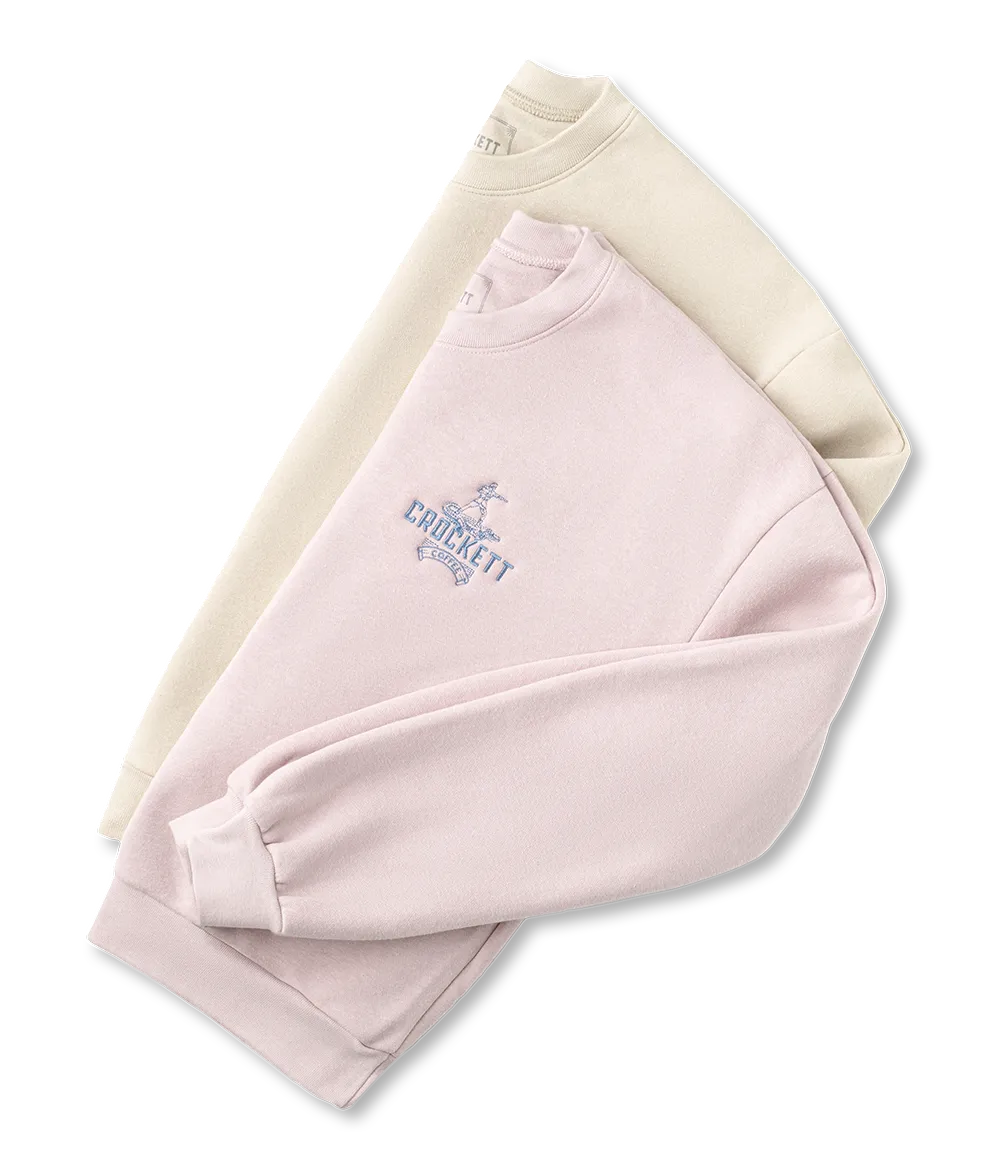 Crewneck sweatshirts in soft pink and cream colors featuring Crockett Coffee logo embroidery on the chest.