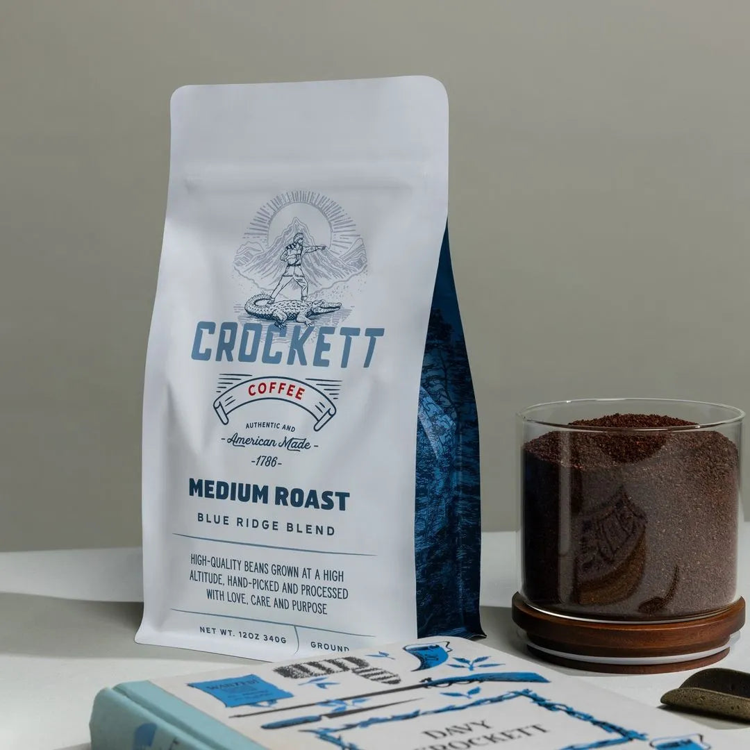 Crockett Medium Roast Blue Ridge Blend coffee bag with a glass jar of coffee grounds on a neutral background