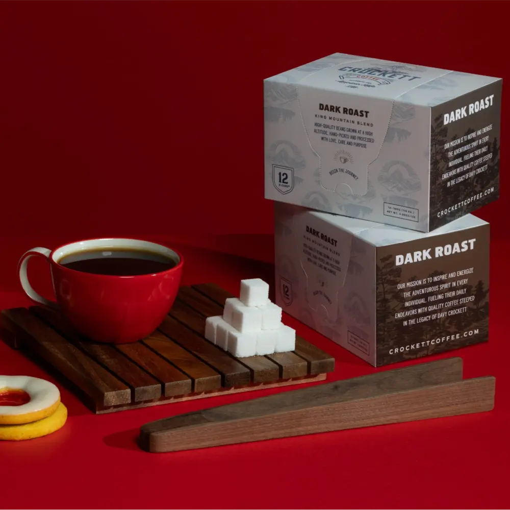 Quality coffee in a red cup served with sugar cubes and Crockett dark roast pods on a bold red background.