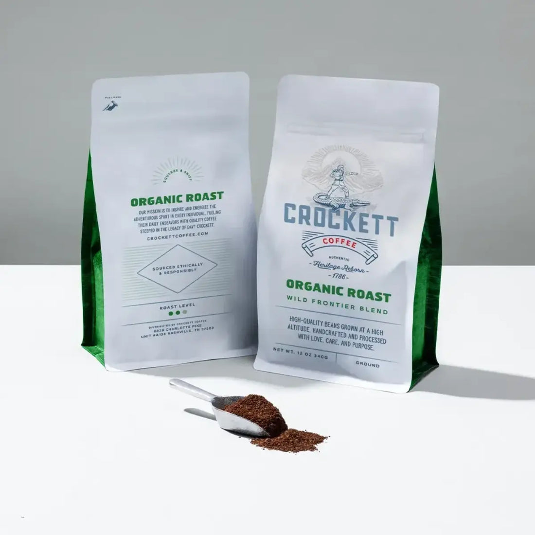 Organic coffee bags labeled "Wild Frontier Blend" with a scoop of freshly ground coffee on a white surface