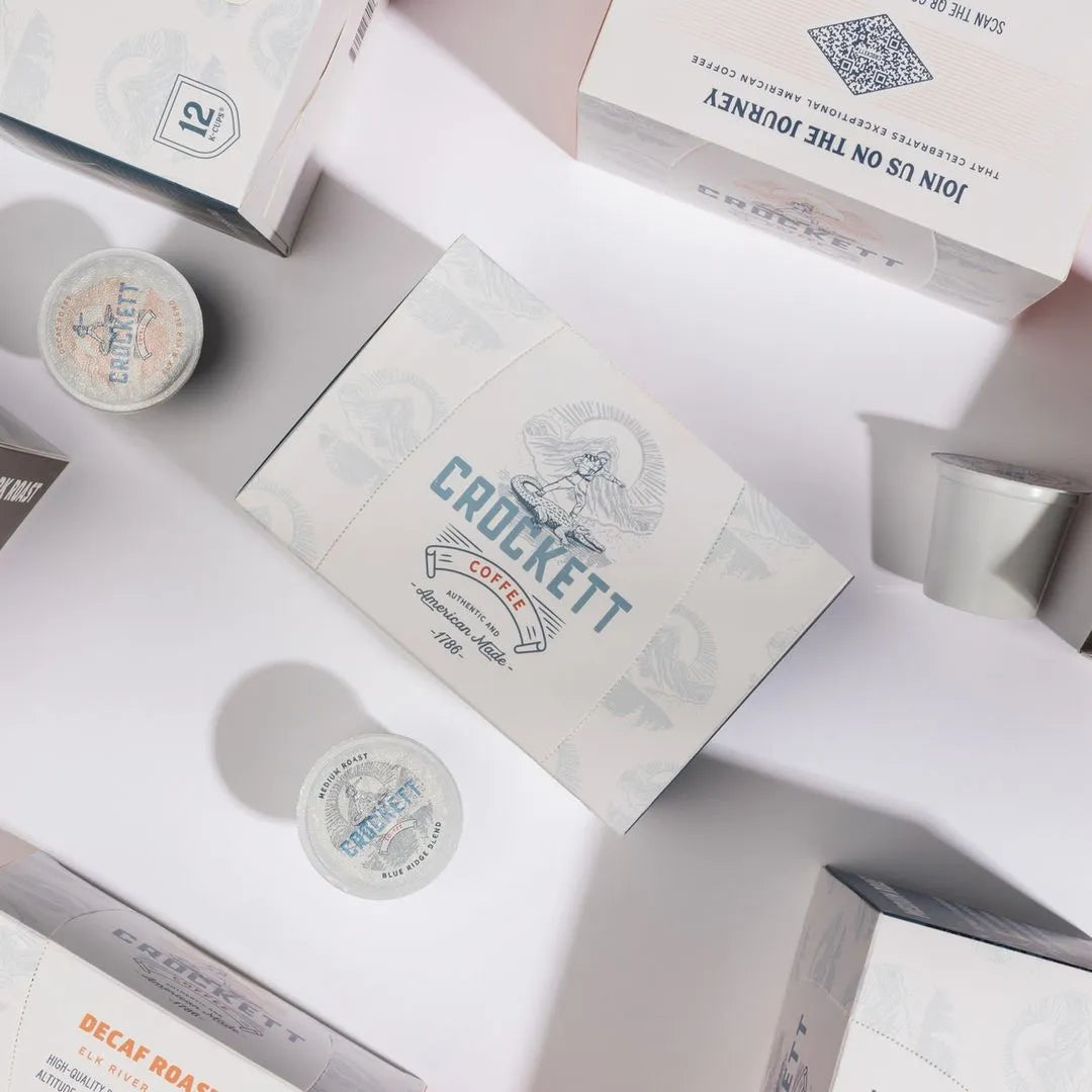 Crockett organic coffee pod boxes and single coffee pods arranged on a white surface with soft lighting.