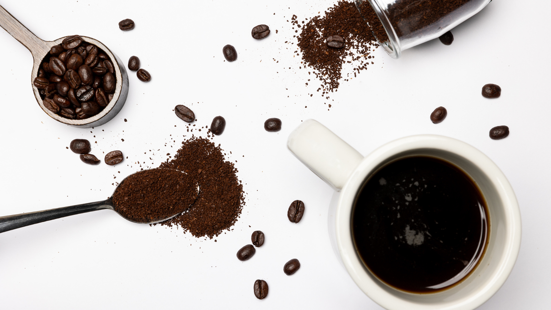 Coffee beans in a measuring cup, ground coffee on a spoon, and a mug full of black coffee.
