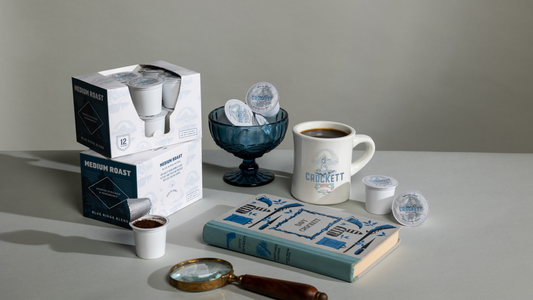 Box of Crockett Coffee K Cups on a table with full mug of coffee.