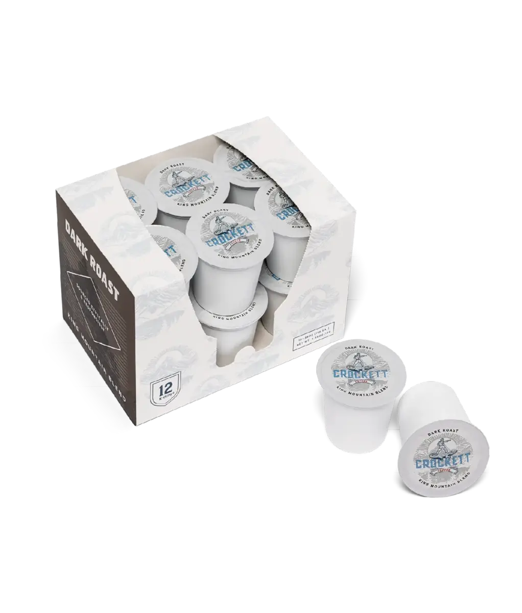 Dark roast coffee K-Cups labeled “Crockett Coffee King Mountain Blend,” with a box of 12 pods and two pods displayed outside the packaging.