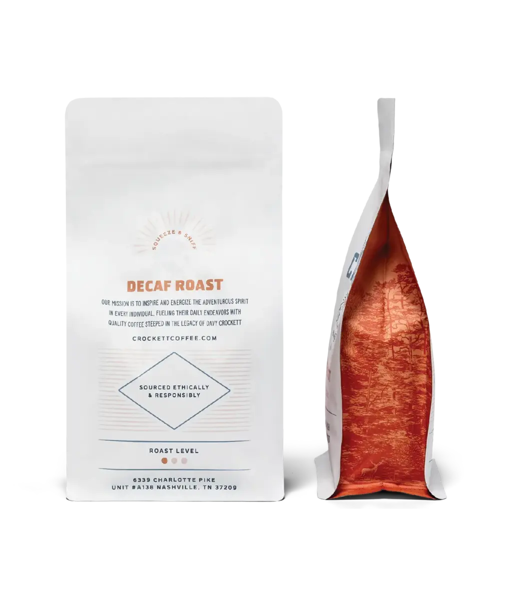 Decaf coffee whole bean bag from Crockett Coffee with orange-toned forest design on the side.