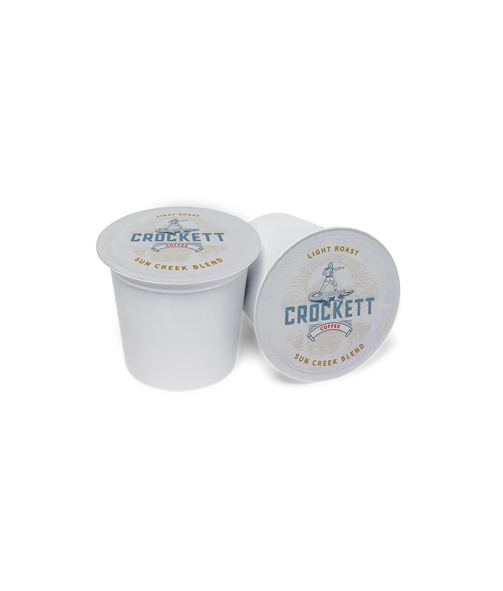 Light roast coffee pods labeled Sun Creek Blend from Crockett Coffee with white lids and blue branding.