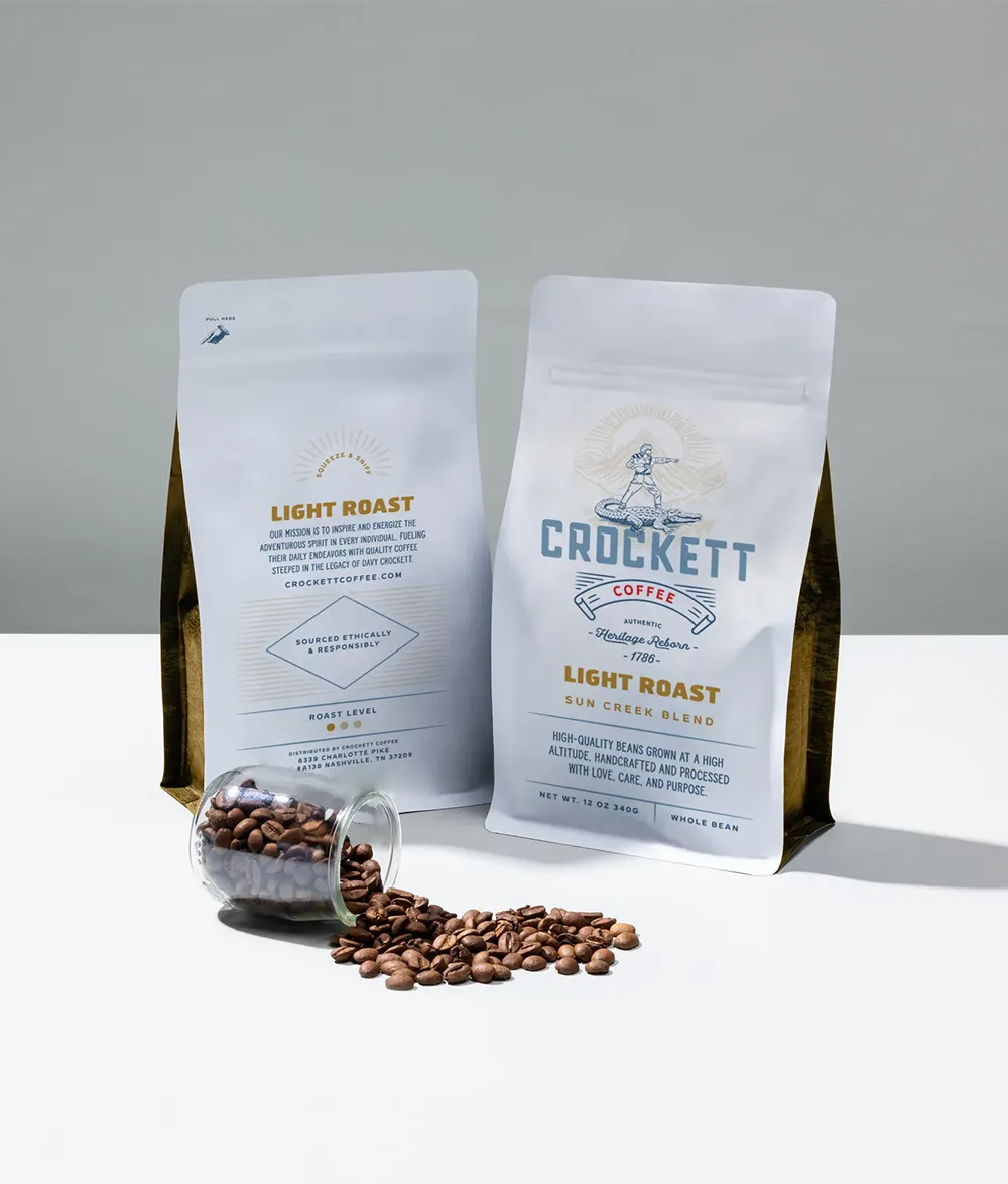 Subscription coffee bags of Crockett Coffee light roast with whole beans and a glass jar of spilled beans.