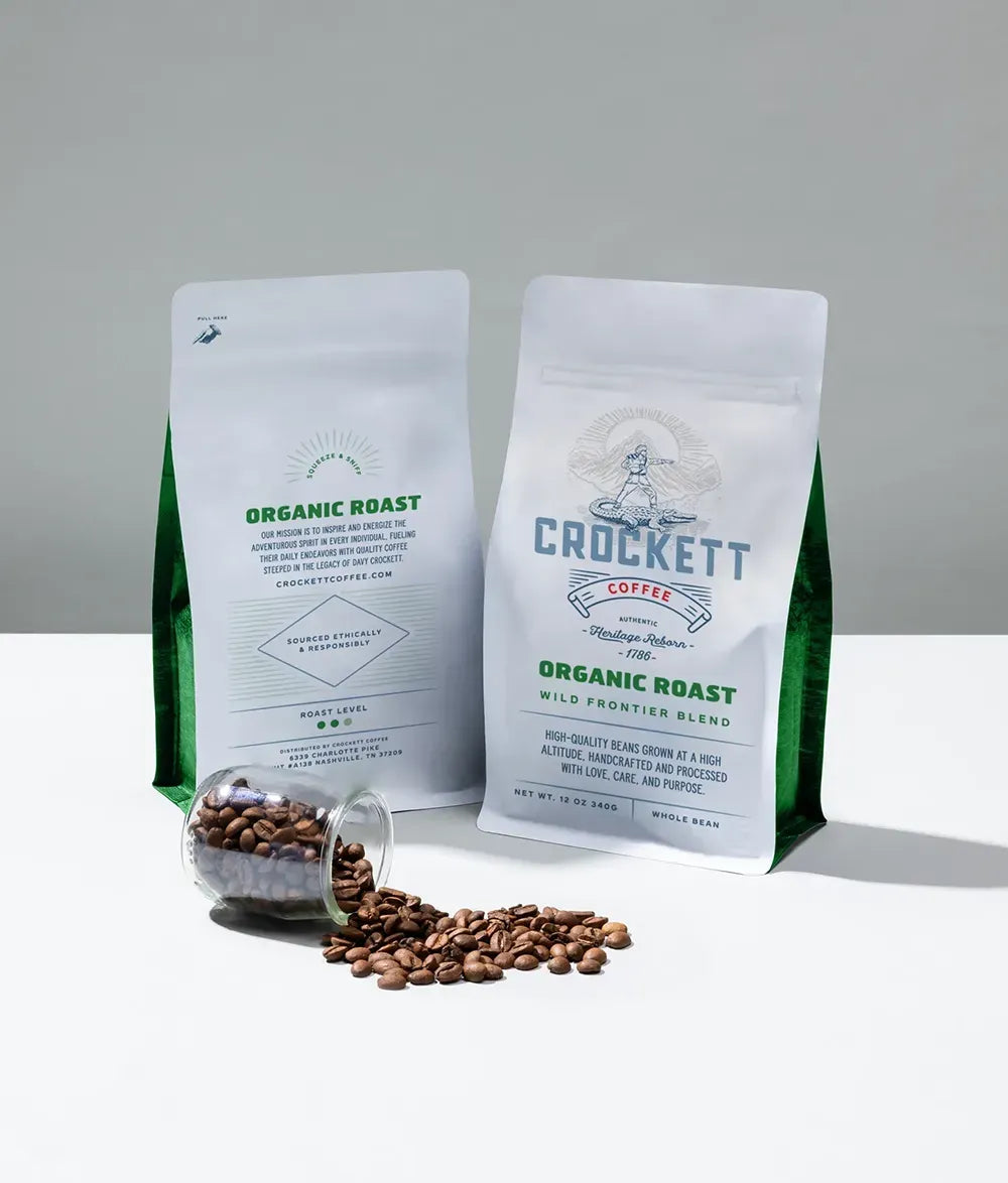 Organic coffee bags featuring Crockett Coffee's "Organic Roast" with spilled coffee beans and green packaging accents.