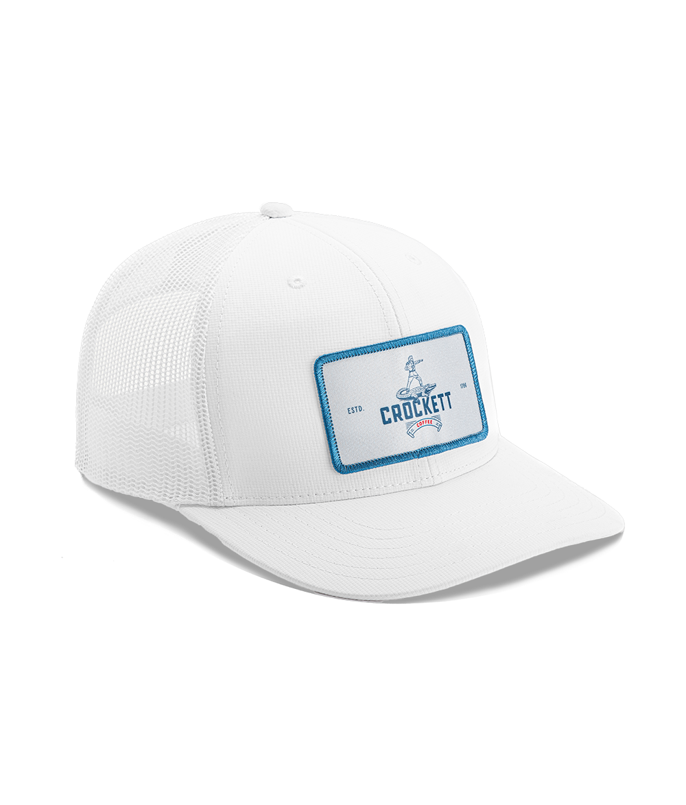 White trucker hat with blue-trimmed Crockett Coffee patch and mesh back panel design.